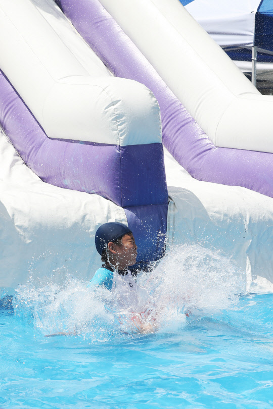 10일 오후 서울 성북구 숭덕초 운동장에 설치된 워터슬라이드에서 어린이들이 즐거운 시간을 보내고 있다. 지역 축제 '성북문화바캉스'는 어른 어린이용 대형풀장, 중형풀장, 워터 슬라이드 등의 물놀이장을 직접 학교운동장에 설치해 오는 11일까지 무료로 운영한다.